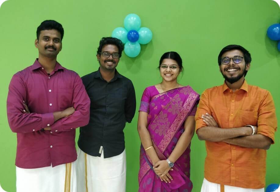 Four members of the Chronus engineering team in front of a green wall with balloons