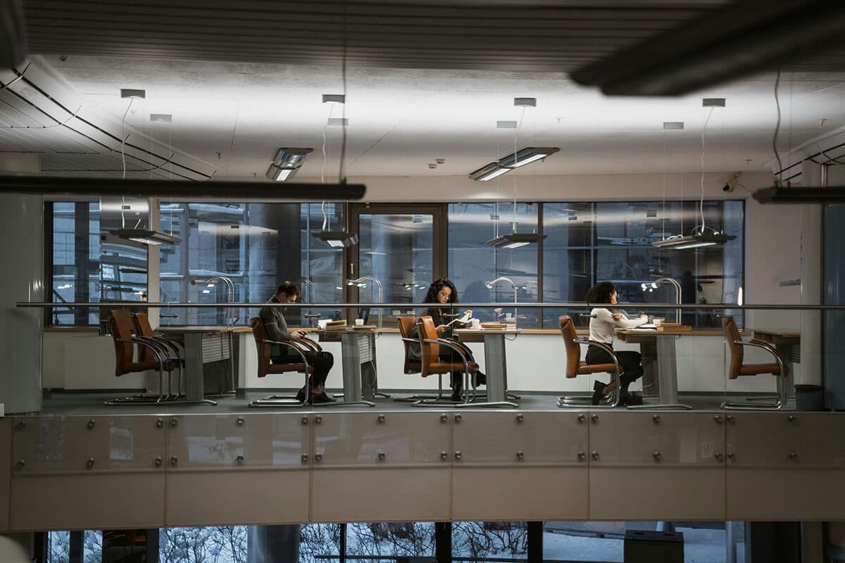 Empty office tables in a modern office high rise. Only a few employees sit in booths.
