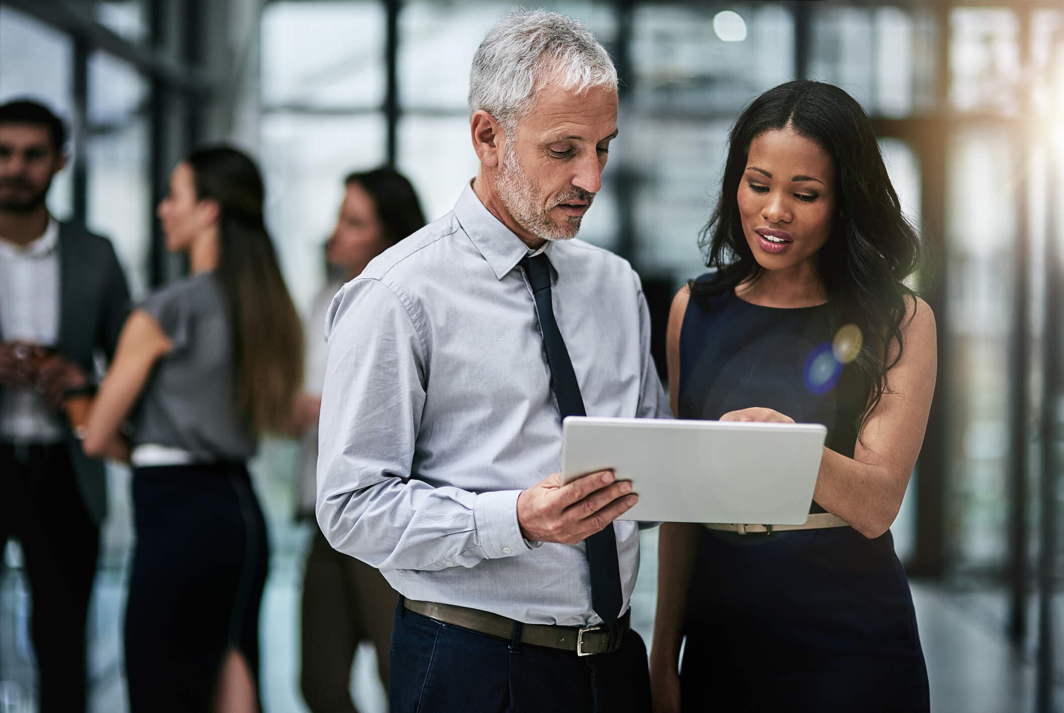 A man and a woman look at a tablet together in an office