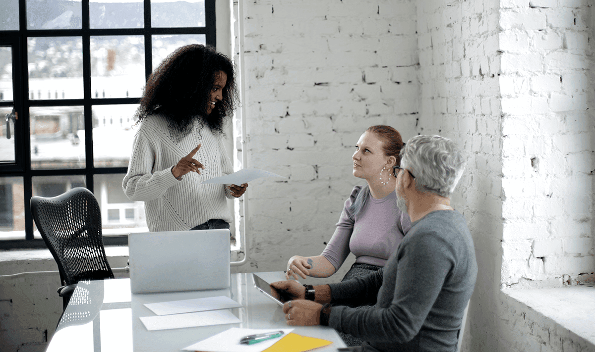 young black female employee presenting to older white colleagues in a conference room
